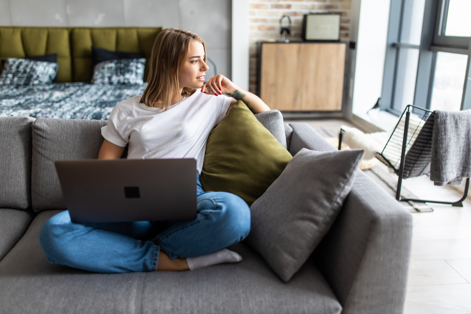 A girl is sitting on a sofa with a laptop